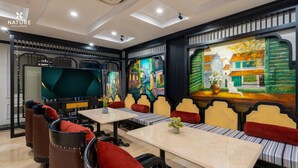 A hotel room with a large TV, comfortable seating, and a colorful mural on the wall.