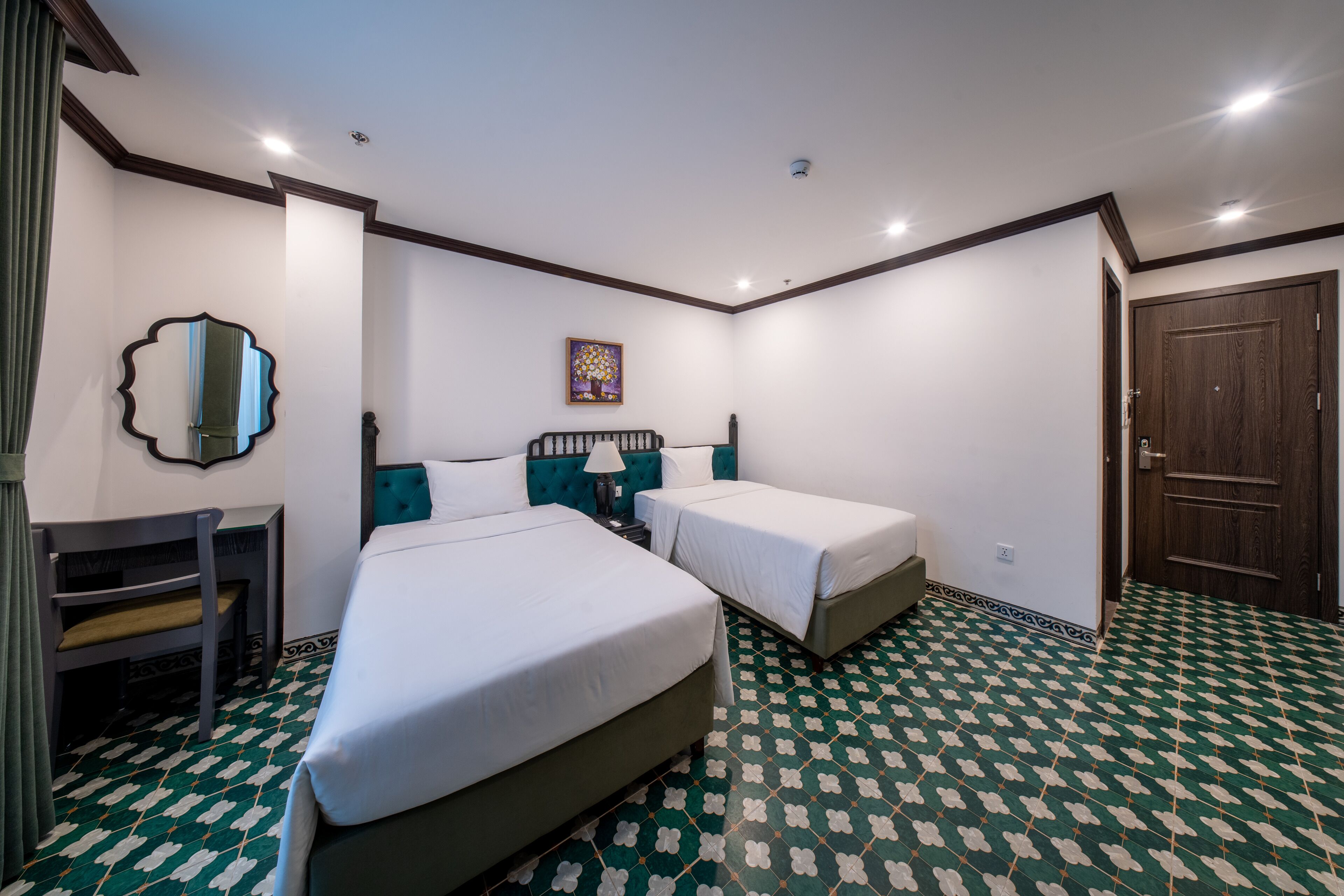 Una habitación de hotel con dos camas individuales, un escritorio, una silla, un espejo y una puerta.