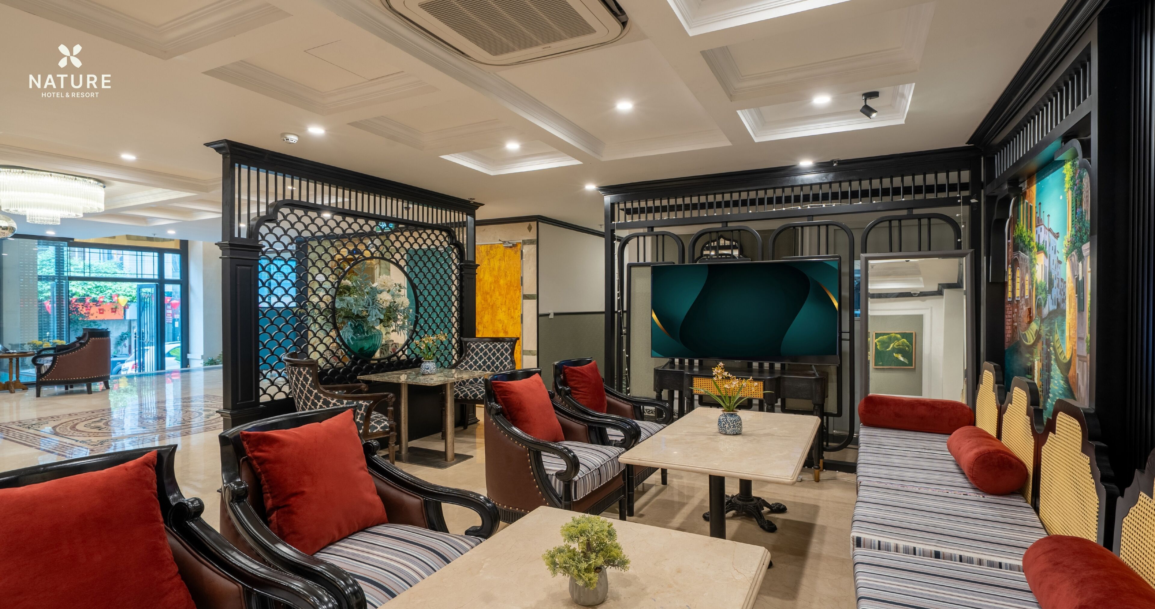 A modern hotel lobby with a mix of seating areas, including sofas and chairs, a central table, and a decorative partition.