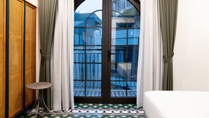 A room with a large arched door, a small round table, and a bed.