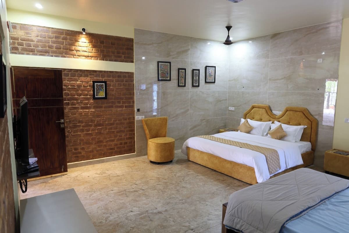 Une chambre d’hôtel avec un mur en briques, un lit avec une tête de lit en bois, une chaise ronde et un ventilateur de plafond.