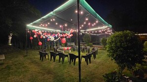 An outdoor patio area with a covered seating arrangement and string lights. - Athulya Resort – Leisure and Luxury cottages from EMBEHolidays (Cheyyur)