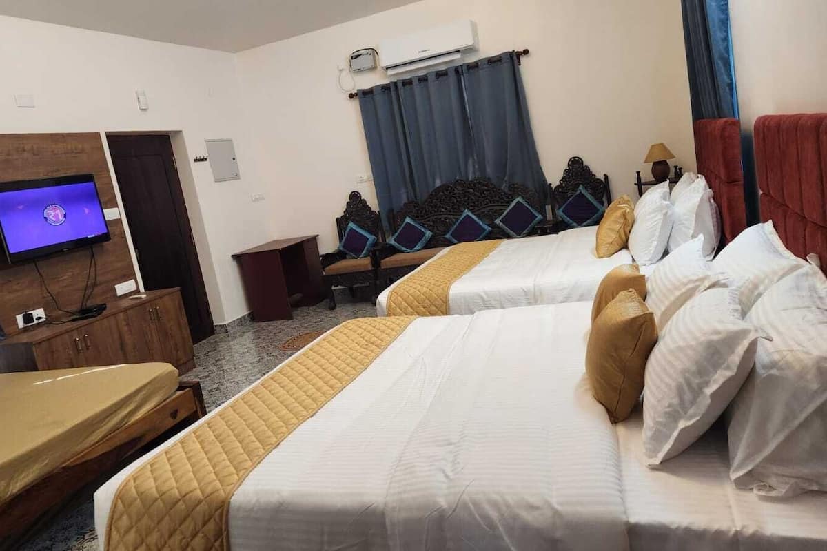 Une chambre d’hôtel avec deux lits, une télévision, un bureau et une armoire.