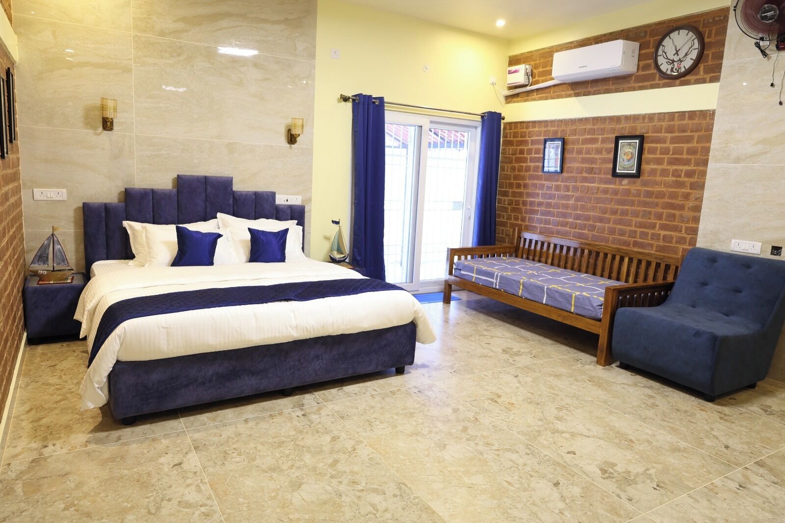 Un dormitorio con una cama grande, un banco de madera y un sillón azul.
