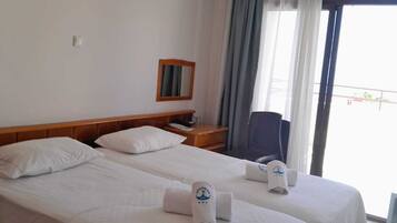A hotel room with two beds, a nightstand, a chair, a mirror, and a view of the outdoors.