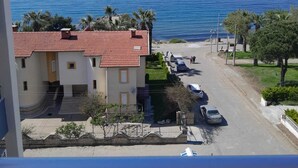 A coastal building with a red-tiled roof, a parking area, and a view of the sea. - Çidihan Hotel (Kuşadası)