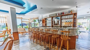 A bar area with multiple stools, a marble countertop, and shelves with glassware. - Çidihan Hotel (Kuşadası)
