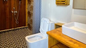 A modern bathroom with a wooden vanity, a white toilet, and a shower area. - Infinity luxuria (Vikarabad)