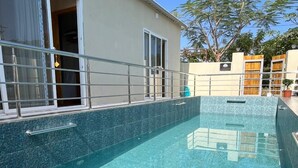 A swimming pool with clear blue water, surrounded by a metal railing. - Infinity luxuria (Vikarabad)