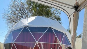 Two people sitting on a wooden bench under a tent-like structure with a geometric design. - Infinity luxuria (Vikarabad)