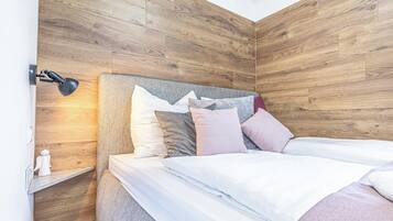 Un dormitorio con cabecera de madera, lámpara de noche y cama bien hecha con varios almohadones.