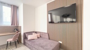 Een moderne slaapkamer met een bed, een bureau en een tv aan de wand.