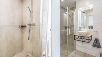 A modern bathroom with a glass-enclosed shower, a sink with a mirror, and a bench.