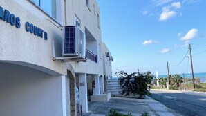 Un edificio con un cartello che indica 'AROS COURT B' e una vista limpida sull'oceano sullo sfondo.