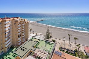 Un edificio de gran altura con varios balcones que dan a una playa y al océano.