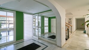 Un interior moderno con un piso de vidrio que da a un balcón, una escalera y un letrero que indica una zona de plantas.