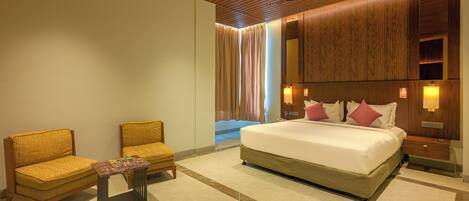 A hotel room with a large bed, two armchairs, a small table, and a wooden ceiling.