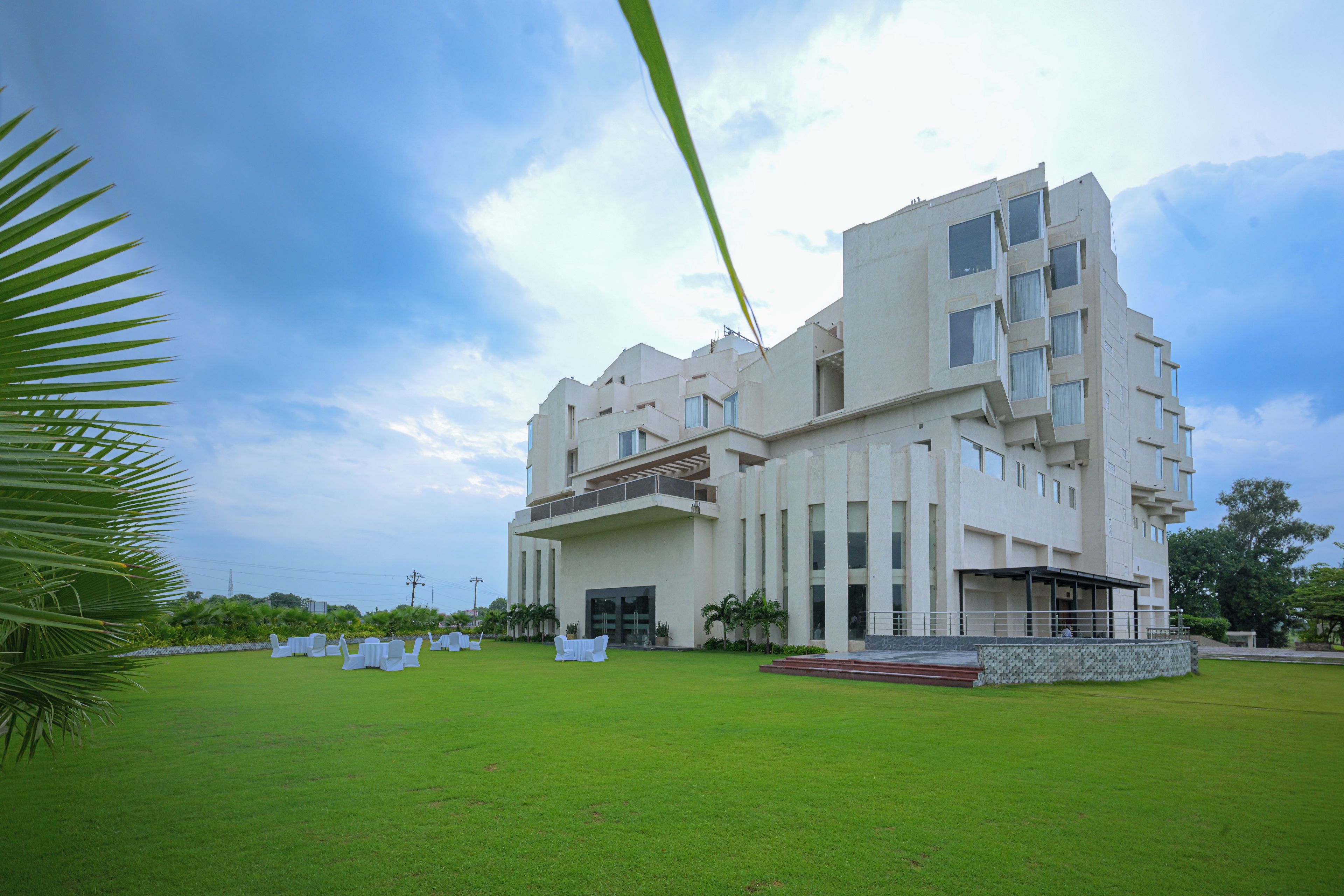 A modern building with a flat roof, multiple windows, and a large lawn area.