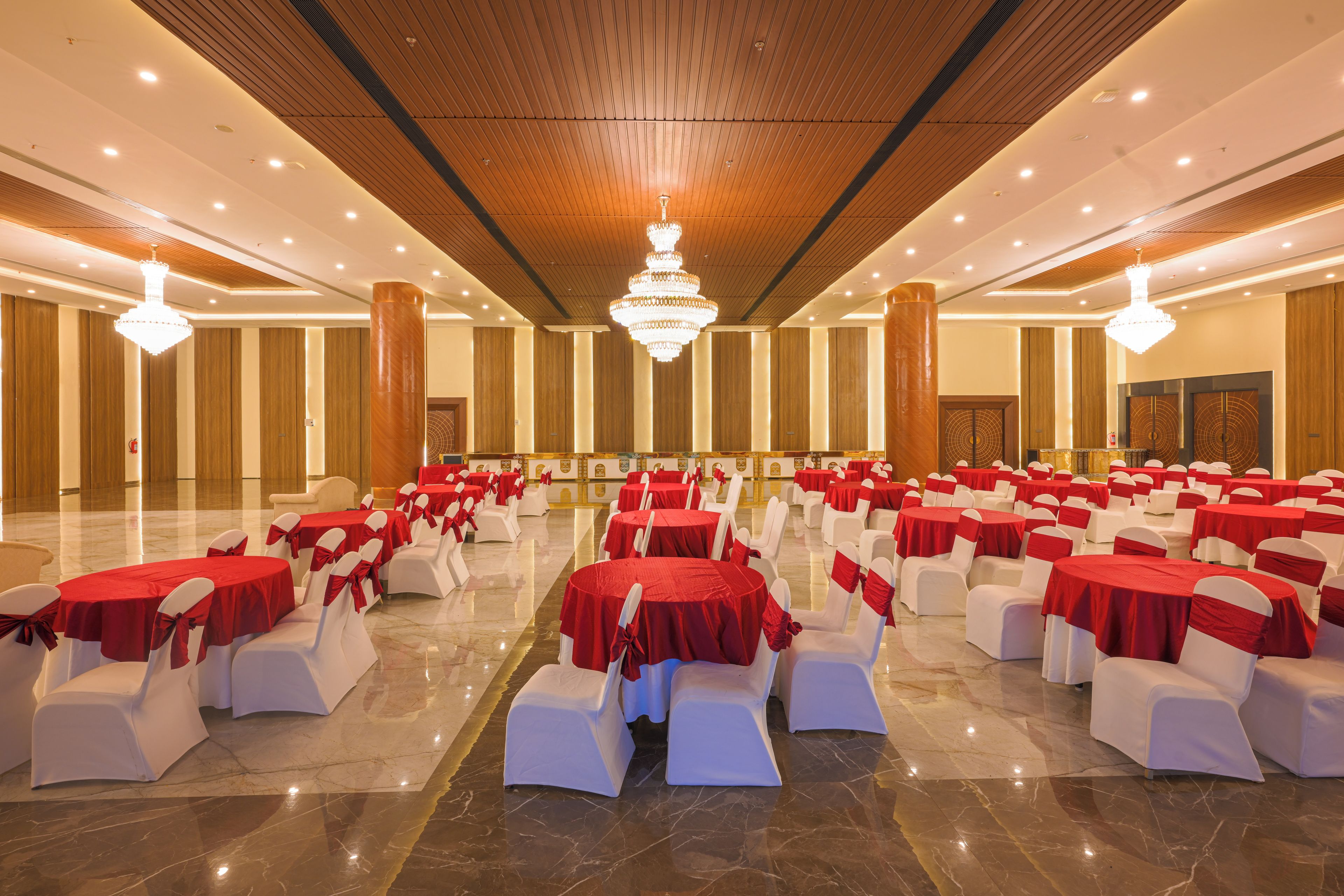 Un salón de banquetes con filas de mesas y sillas, una araña y un piso de mármol pulido.