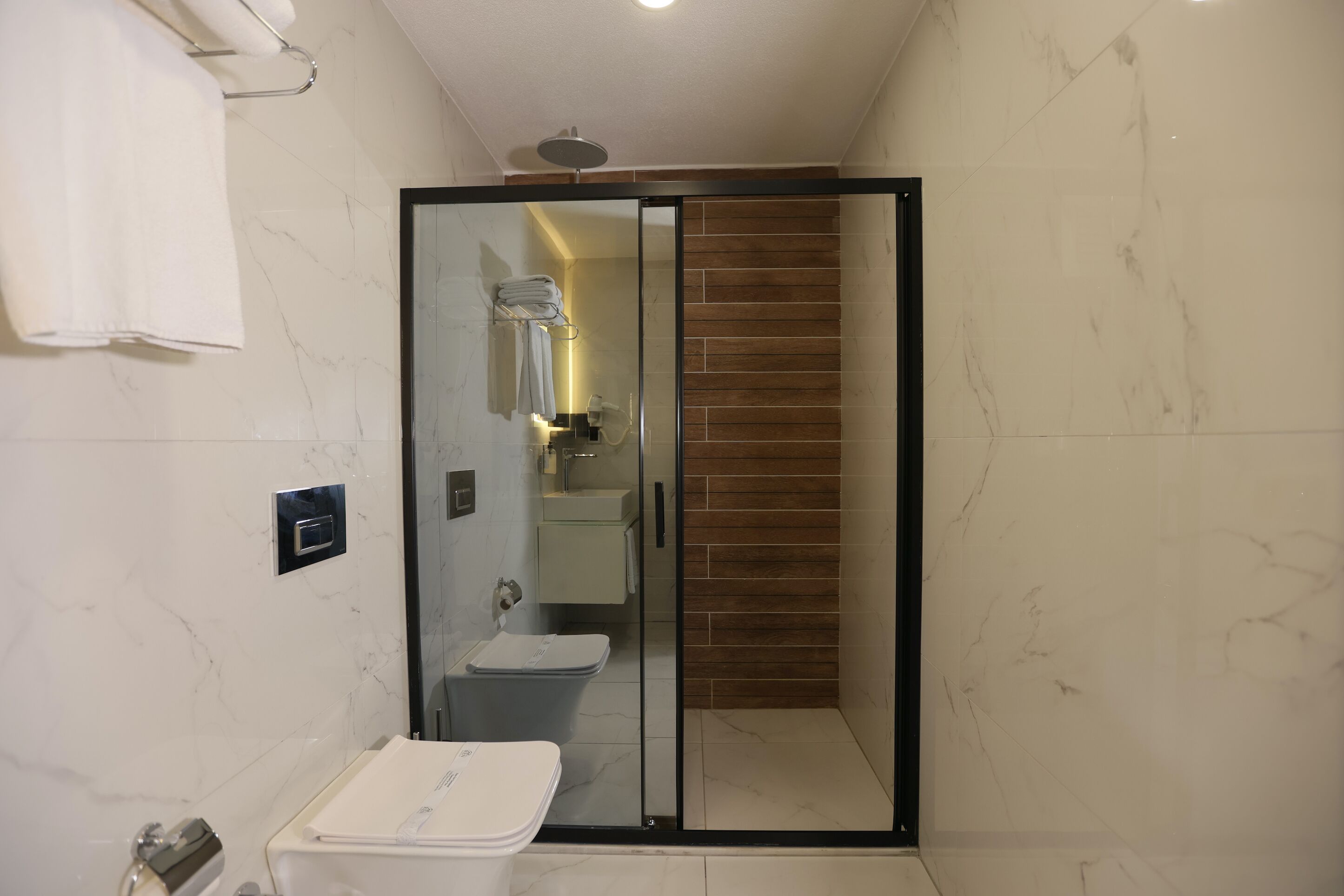 Un baño moderno con cabina de ducha de vidrio, un lavamanos blanco y un inodoro.