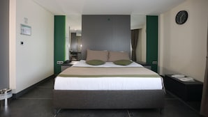 Habitación de hotel con una cama grande, una mesita de noche, un reloj y un espejo en la pared.