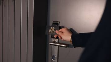 A hand inserting a key into a door lock with a business hotel logo.
