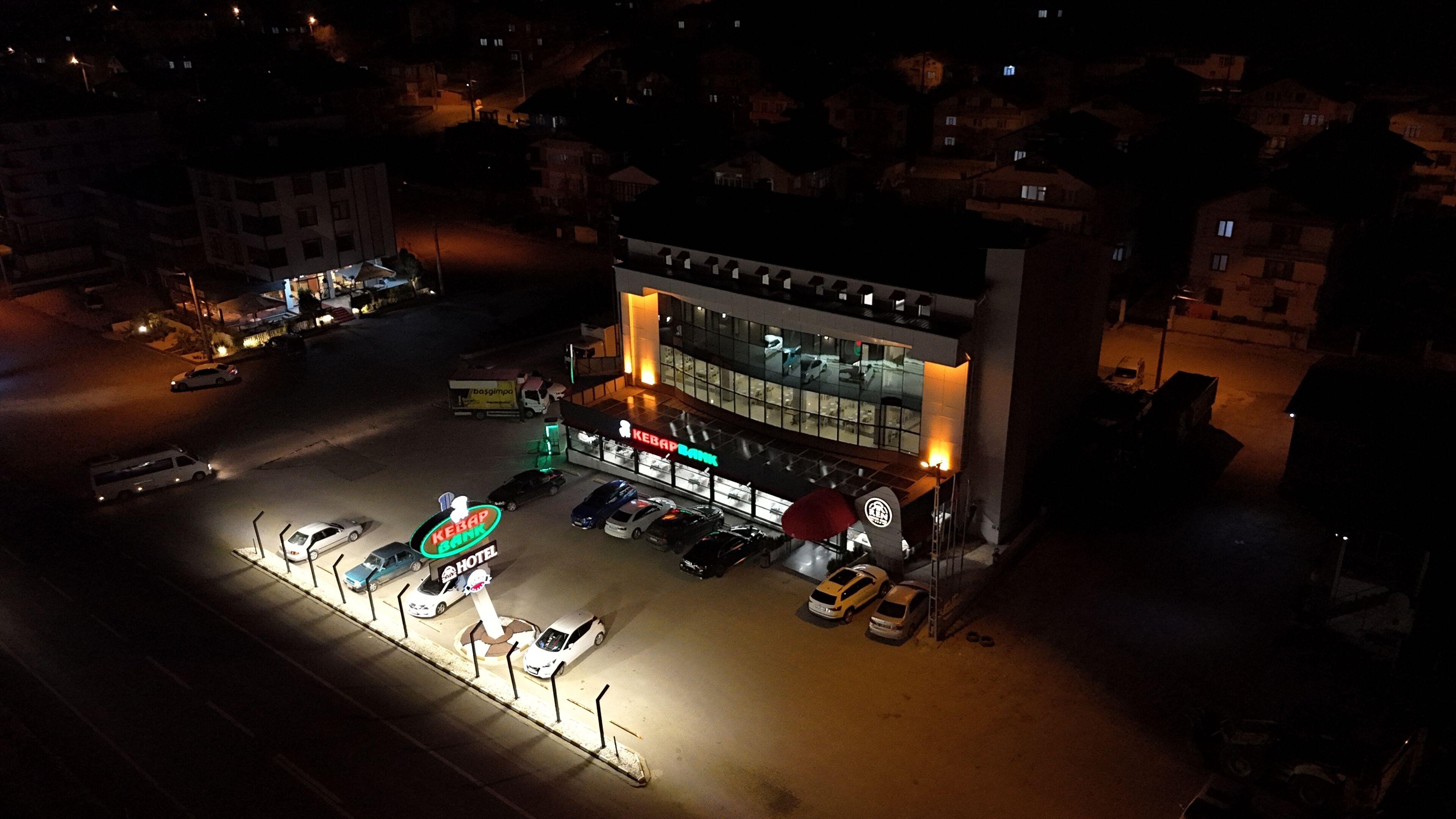 A hotel with a prominent sign, a parking lot, and a street view at night.