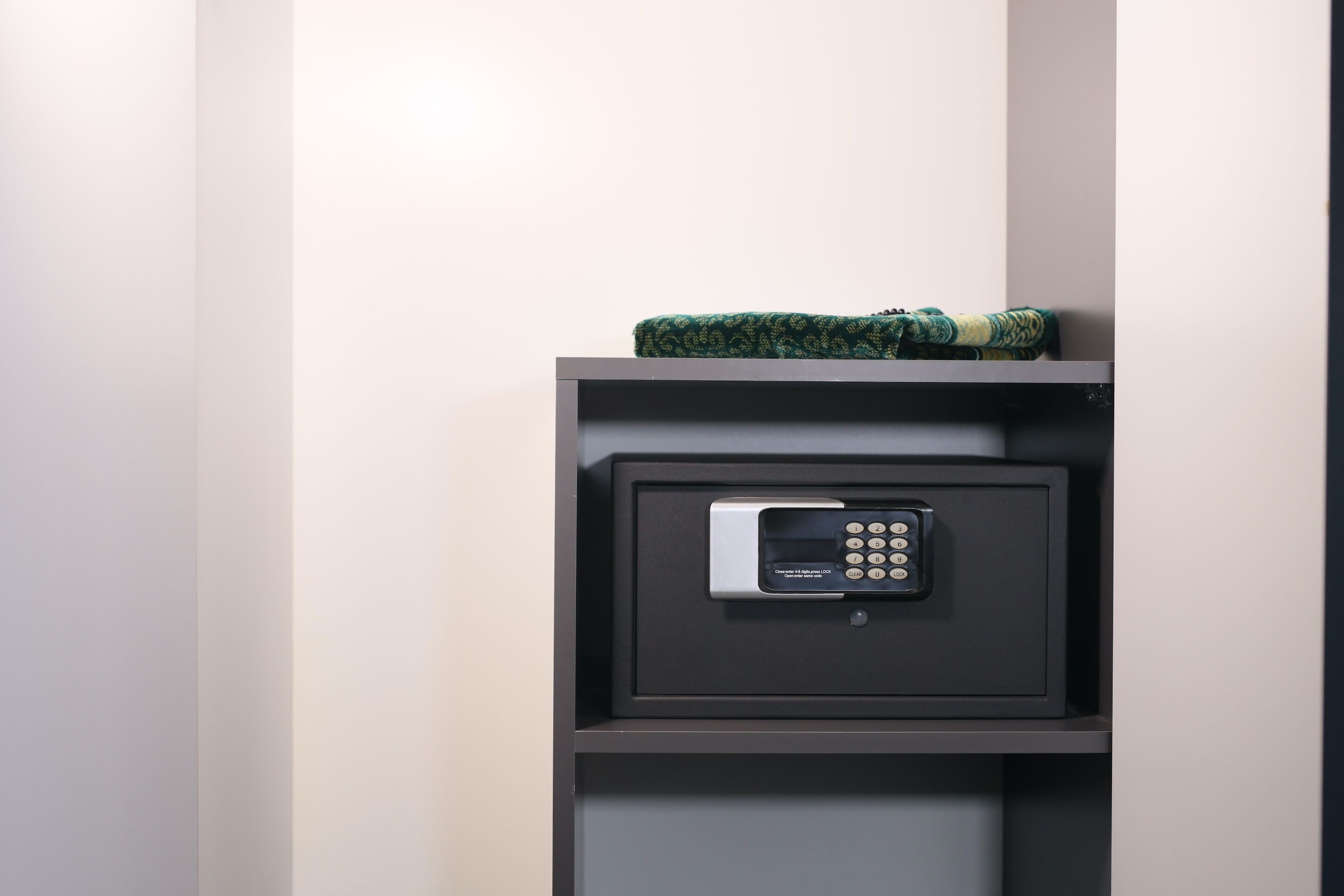 A secure safe in a dark-colored cabinet with a digital keypad lock.