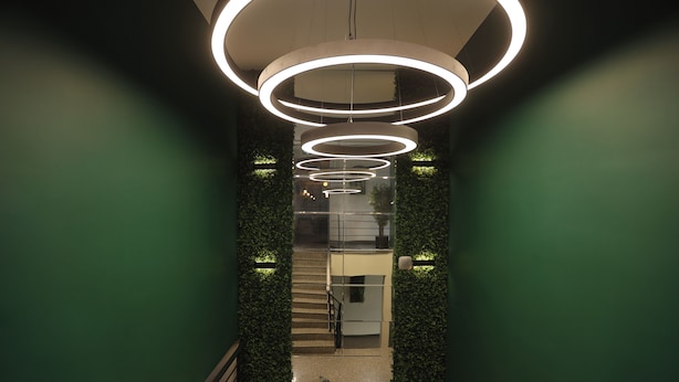 Un interior moderno con lámparas circulares, una escalera y detalles verdes en la pared.