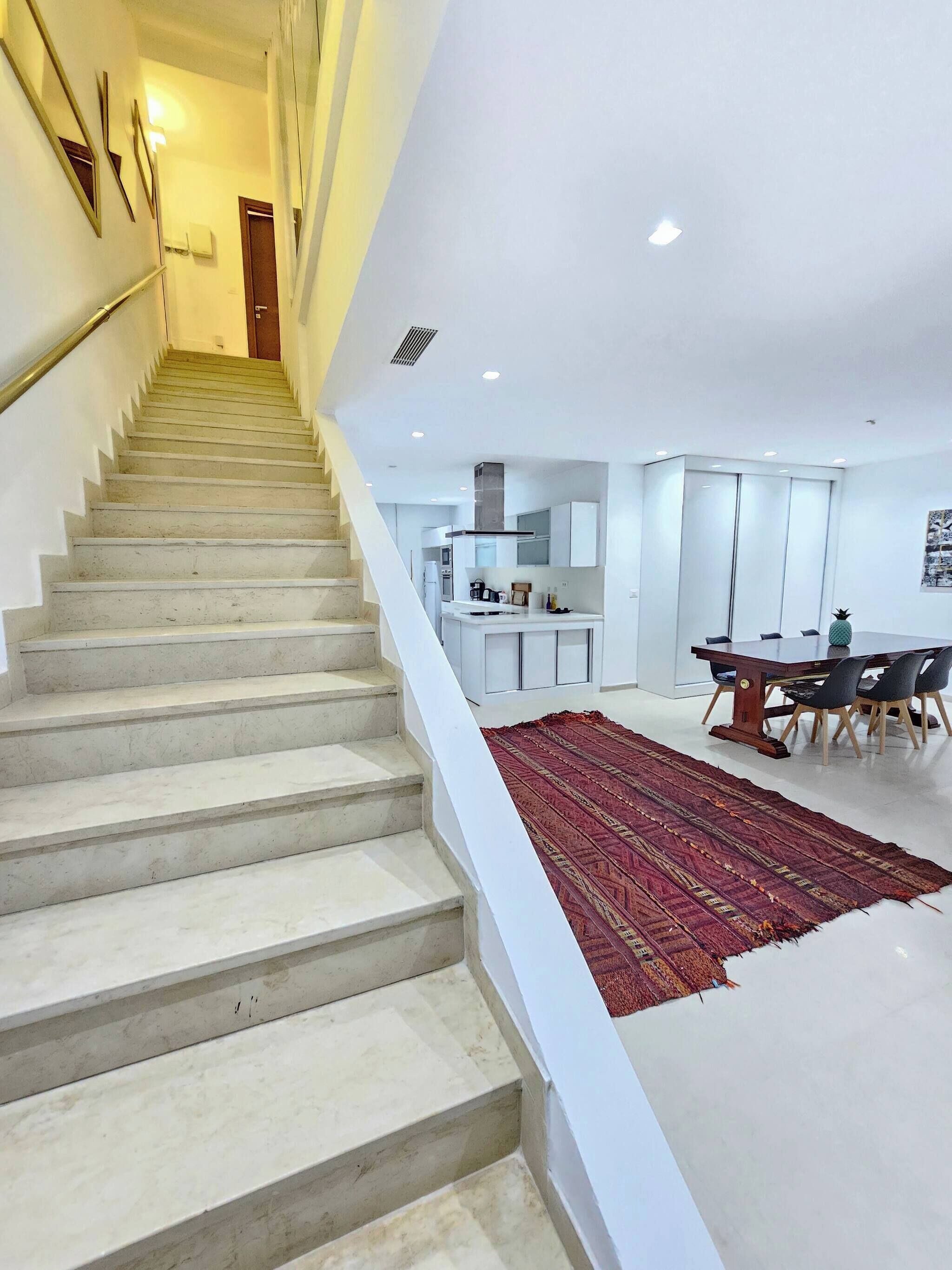 Una escalera conduce a una cocina moderna con comedor.