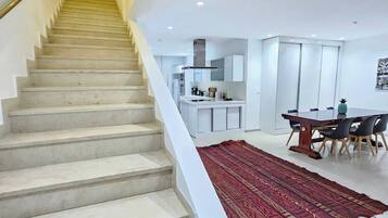 Una escalera conduce a una cocina moderna con comedor.