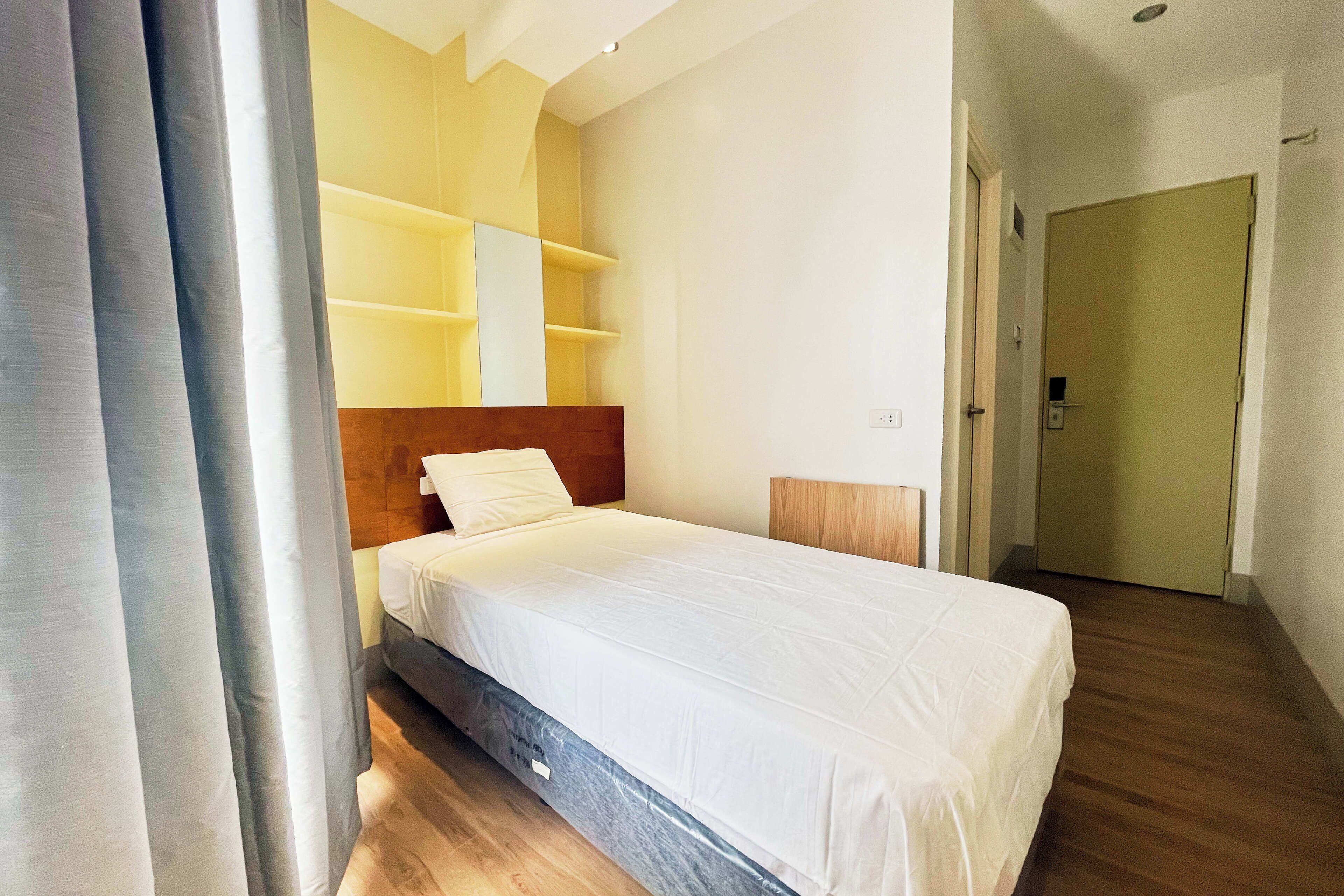 Un dormitorio con cama, cabecera de madera y estanterías empotradas.