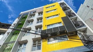 Ein mehrstöckiges Gebäude mit einer gelb-weißen Fassade, Außentreppen und sichtbaren Fenstern.