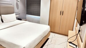 A modern bedroom with a large bed, a wardrobe, a bedside table, and a wall-mounted TV. - Hotel Casa Del Sol (Raipur)