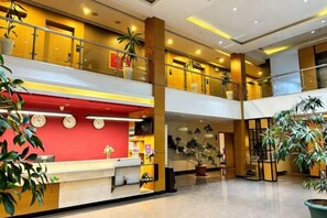 A hotel lobby with a reception desk, multiple floors, and potted plants. - Taishan guest house (Addis Ababa)