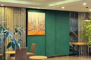 A modern interior with a green accent wall, a painting, and a staircase. - Taishan guest house (Addis Ababa)
