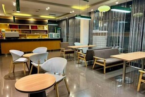A modern cafe with round tables and chairs, a bar area, and a view through a curtain. - Taishan guest house (Addis Ababa)