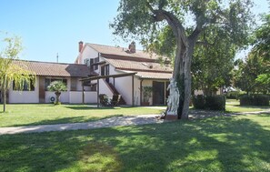 Uma casa de dois andares com telhado de telhas, varanda coberta e uma estátua no jardim.