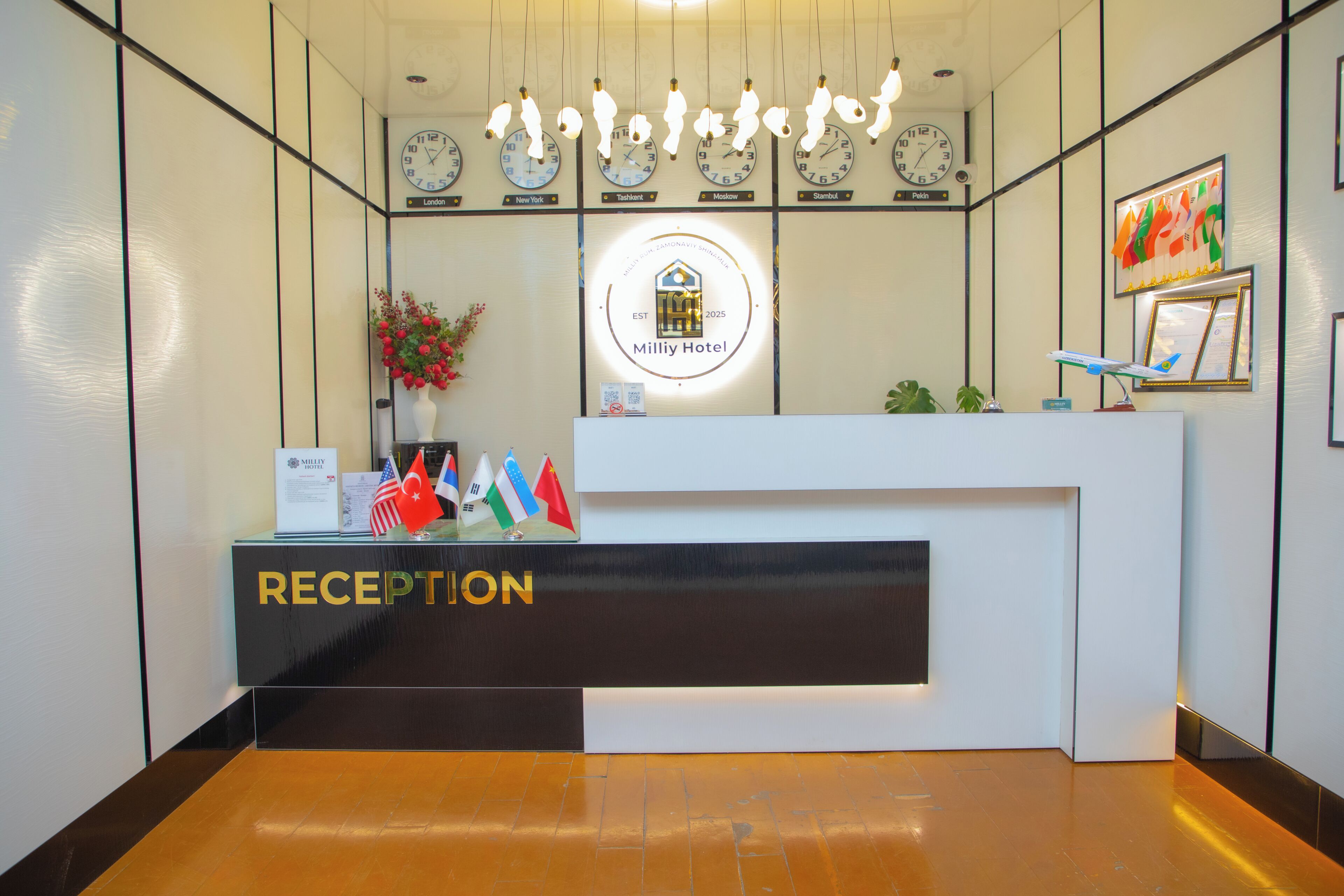A reception desk with a clock, flags, and a logo for Milliy Hotel.
