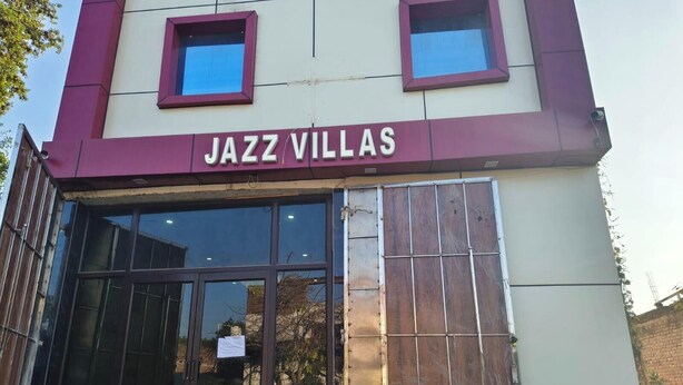 The exterior of a building named 'JAZZ VILLAS' with large glass windows and a maroon and white facade. - Hotel Jazz Villas (Agra)