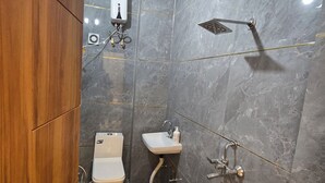 A compact bathroom with a toilet, sink, shower, and a wooden cabinet. - Hotel Jazz Villas (Agra)