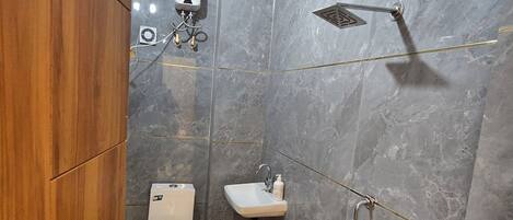 A compact bathroom with a toilet, sink, shower, and a wooden cabinet.