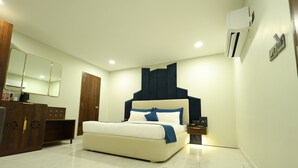 A modern bedroom with a large bed, a wardrobe, a mirror, and a wall-mounted air conditioner. - Hotel Metro Agra (Agra)