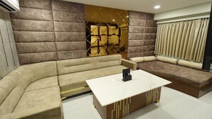 A modern living room with a sectional sofa, a coffee table, and a decorative wall panel. - Hotel Metro Agra (Agra)