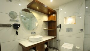 A modern bathroom with a white sink, wooden vanity, a large mirror, and a toilet. - Hotel Metro Agra (Agra)