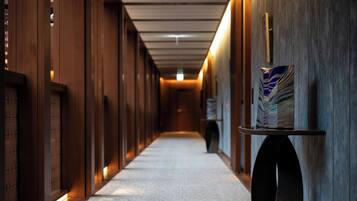 A corridor with wooden paneling, a carpeted floor, and a wall-mounted display case.