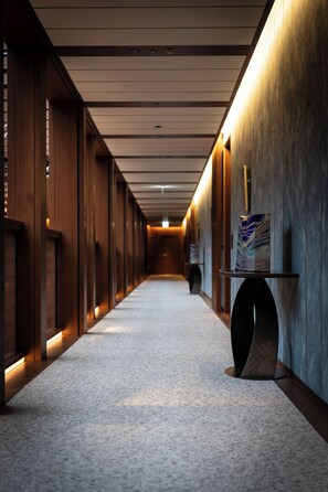A corridor with wooden paneling, a carpeted floor, and a wall-mounted display case. - THE PASONA natureverse retreat (Awaji)