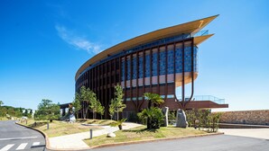 A modern building with a curved facade, large windows, and a prominent entrance. - THE PASONA natureverse retreat (Awaji)