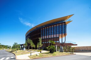 A modern building with a curved facade, large windows, and a prominent entrance. - THE PASONA natureverse retreat (Awaji)
