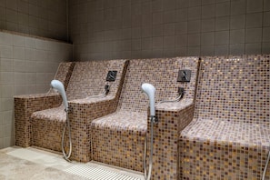 A row of three shower stalls with tiled walls and benches, equipped with handheld shower heads. - THE PASONA natureverse retreat (Awaji)
